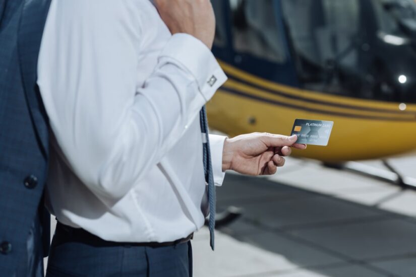 Man Holding A Credit Card Standing Next To A Helicopter